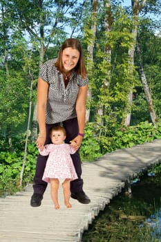 baby taking first steps with mother help