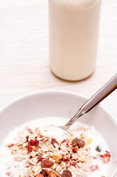Cereal in a bowl and a bottle of milk