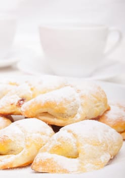 Closeup of homemade jam filled crescent rolls and white cups of tea