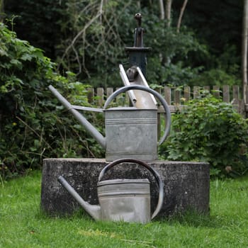 Old fountain with watering cans in the garden