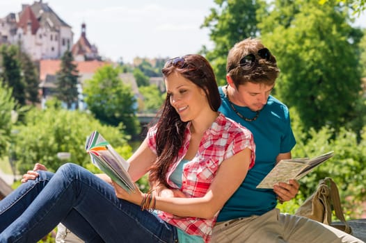 Young happy couple reading map city guide embrace smiling travel