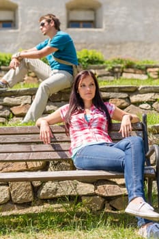 Young people relax in park sitting bench sunny day
