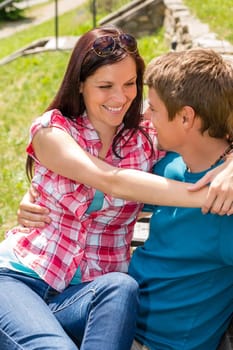Happy young couple flirting on bench in sunny park smiling