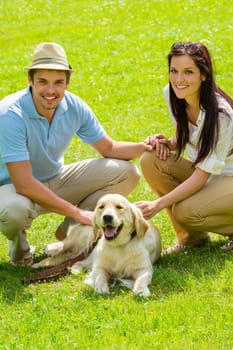 Young happy couple with Labrador dog smiling in park