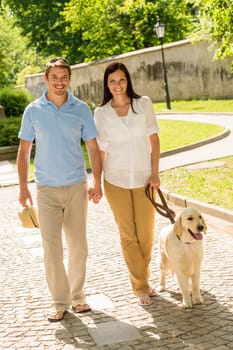 Couple in love walking Labrador dog in park sunny day