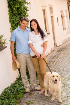 Modern couple with Labrador dog in romantic city smiling together