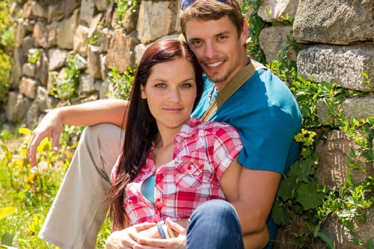 Young couple in love sitting leaning against wall sunny day