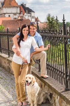 Young couple with dog posing at historical town sunny day