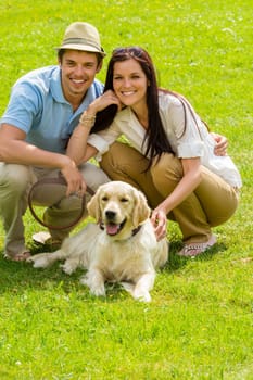 Young happy couple with Labrador dog sitting on grass