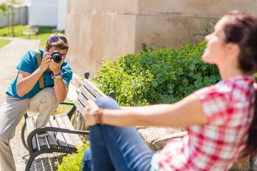 Man taking pictures of woman sitting on bench in park