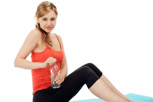 Blonde young sportswoman opens a bottle of water on white background