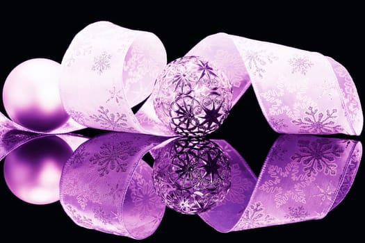 Violet baubles and bow on black mirror