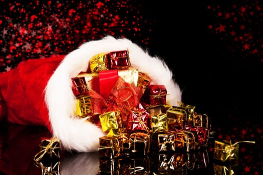 Gifts falling out of Santa hat on black background