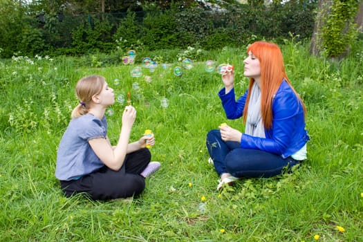 Little girl and young woman blowing soap bubbles