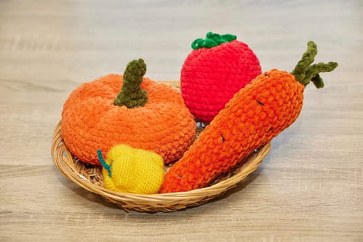 Cute knitted vegetables toys on a wicker plate.