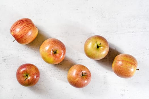 Tabletop view, six shiny apples (kiku variety) on white working board