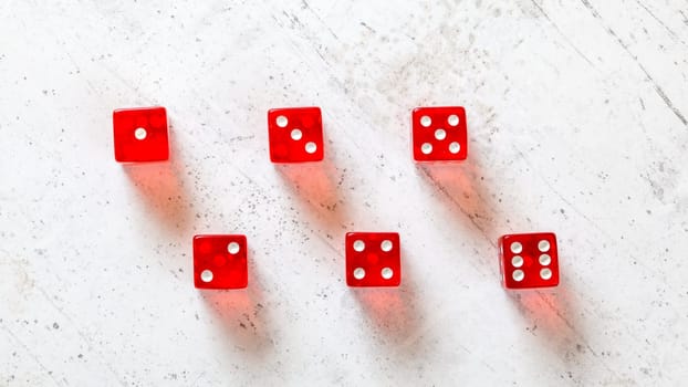 Red translucent craps dices on white board, showing all numbers from 1 to 6 photographed from above