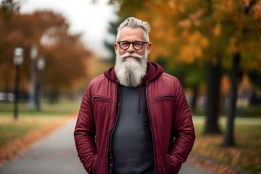 a positive mature man in vision glasses who is happily walking through the autumn park. His relaxed posture and positive facial expression indicate complete harmony with the surrounding nature.