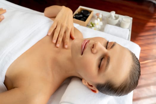 Caucasian woman customer enjoying relaxing anti-stress spa massage and pampering with beauty skin recreation leisure in day light ambient salon spa at luxury resort or hotel. Quiescent