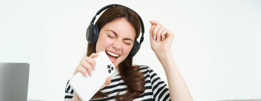 Carefree woman singing into smartphone microphone, playing mobile karaoke app, having fun, isolated on white background.