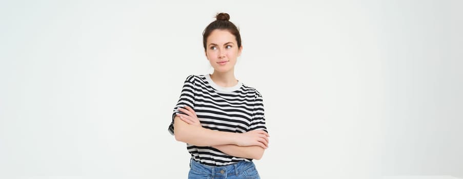 Portrait of young stylish woman, 25 years old, looking upbeat and motivated, posing for photo against white background.