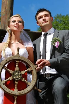 wedding couple on the antique ship with wooden steering wheel