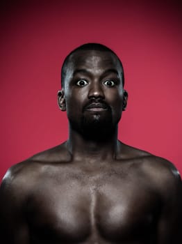 one young dumb african man topless portrait in studio on red background