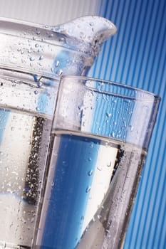 Composition with two glass of mineral water and jug on blue background