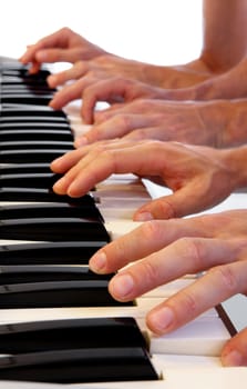 Six hands playing simultaneously on a grand piano with bright white background