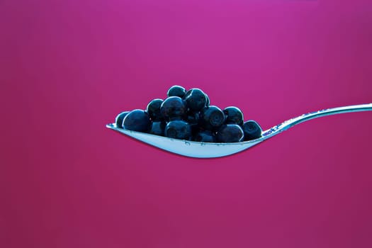 Fresh blueberry on metal chromed spoon on background