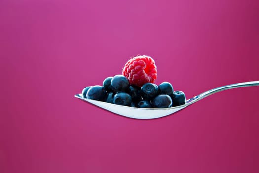 Fresh blueberry and raspberry on metal chromed spoon