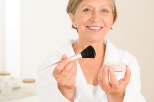 Mature woman hold brush and make-up powder in the bathroom