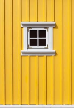 Bright yellow timber wall with a small window