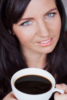 Brunette woman enjoying a cup of black coffee
