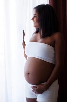 Young beautiful pregnant indian touching her tummy