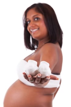Young pregnant indian woman holding baby shoes, isolated on white background
