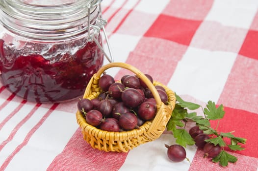 Basket with berries of a red gooseberry and jam