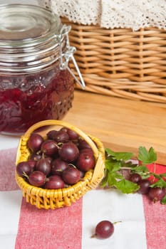 Basket with berries of a red gooseberry and jam