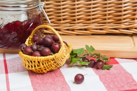 Basket with berries of a red gooseberry and jam