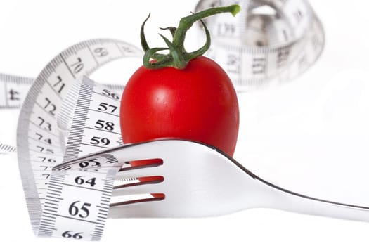 Eat more vegetables - lose weight with measure - measuring tape through a fork with a tomato against a white background