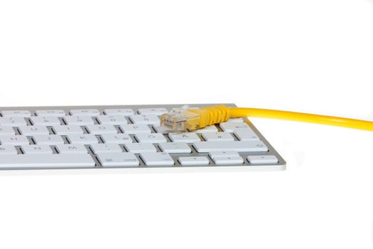 Network cable to keyboard - Yellow network cable lying on modern computer keyboard against white background
