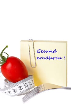 Sticky note with inscription: Healthy Eating - Yellow sticky note with the inscription: Healthy Eating with paper clip behind a tomato with measuring tape and a fork against a white background