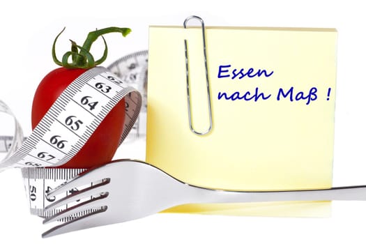 Made-to-measure food - Yellow notepad with the inscription: Made-to-measure food with paper clip behind a tomato with measuring tape and a fork against a white background