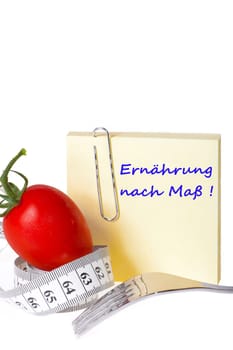 Made-to-measure nutrition - Yellow notepad with the inscription: Made-to-measure nutrition with paperclip behind a tomato with measuring tape and a fork against a white background