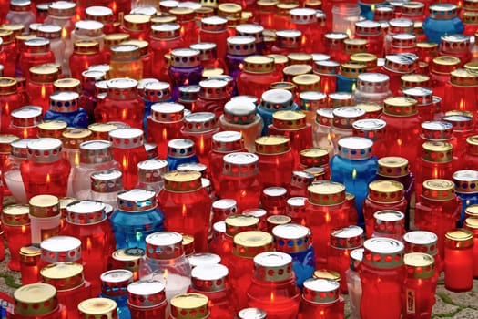 A lot of illuminated votive candles glows on a grave lantern