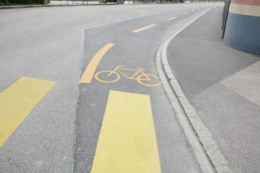 Yellow painted sign for bikes on asphalt