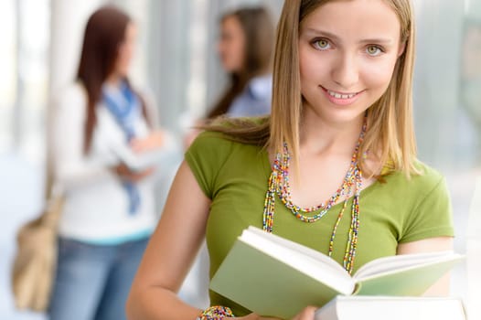 Female student reading book at high school library hall