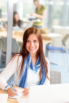 Female student smiling take notes at high school study room