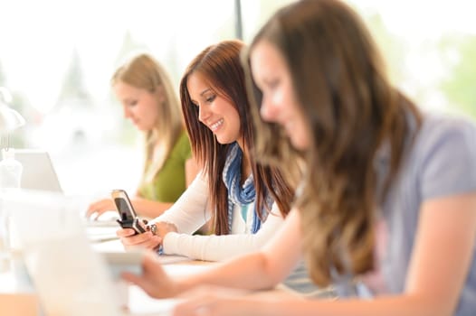 Young student girl in classroom using phone write message