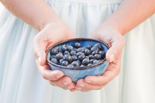 Girl holding a bowl of blueberries